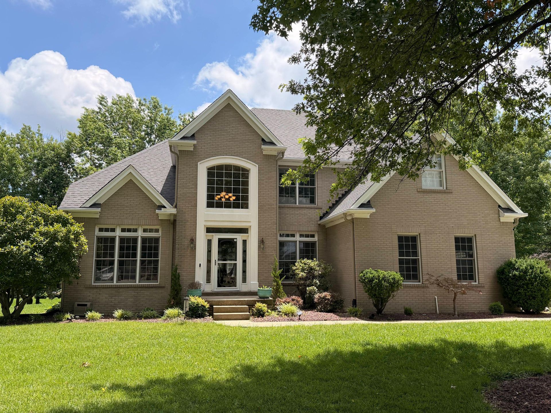 Front elevation of an upscale brick home highlighting a newly installed gray asphalt shingle roof wi 