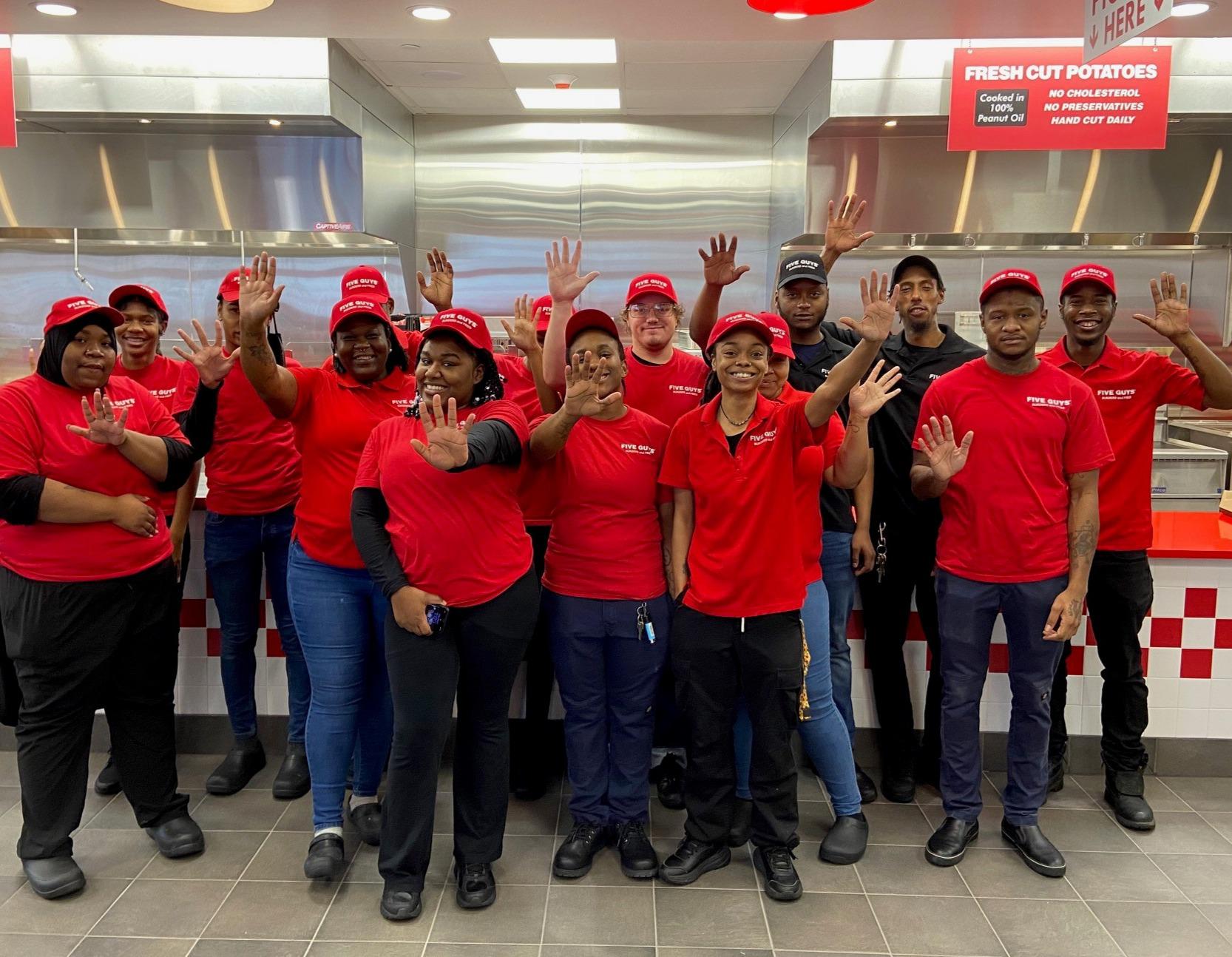 Crew members pose for a photograph ahead of the grand opening of the Five Guys restaurant at 3714 Spruce Street in Philadelphia, Pennsylvania.