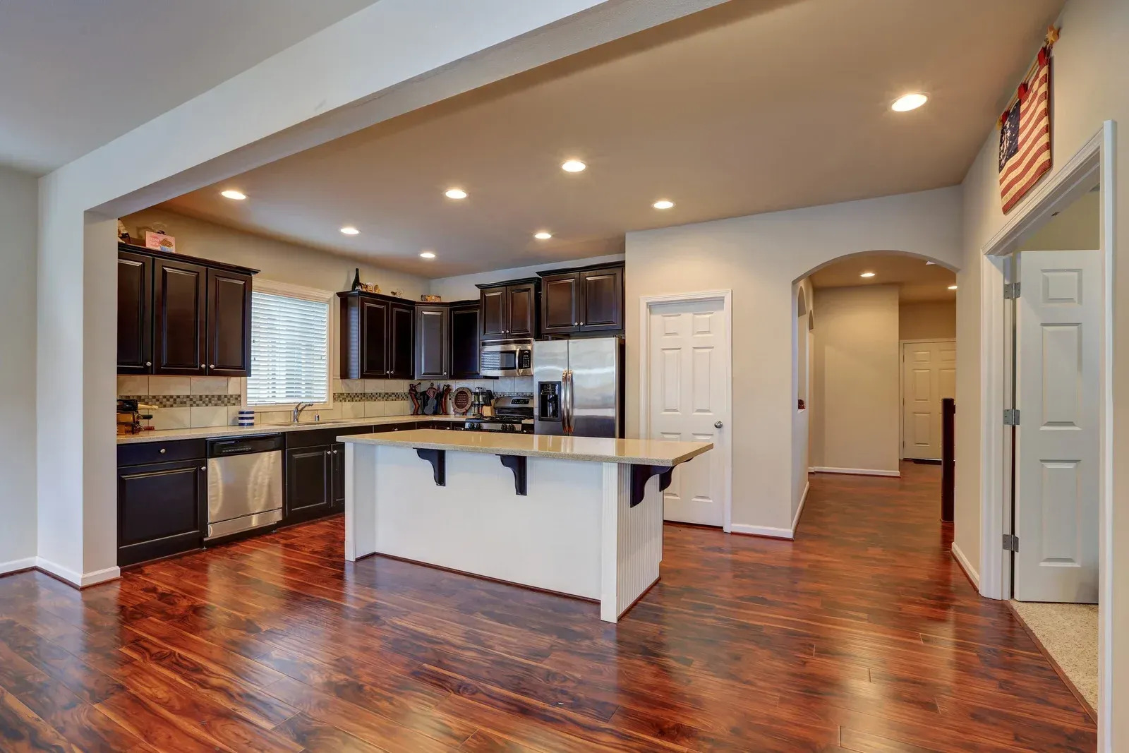 Beautiful kitchen renovation featuring dark cabinetry, hardwood flooring, recessed lighting, and a spacious island. The updated design blends functionality, comfort, and modern aesthetics for everyday living.