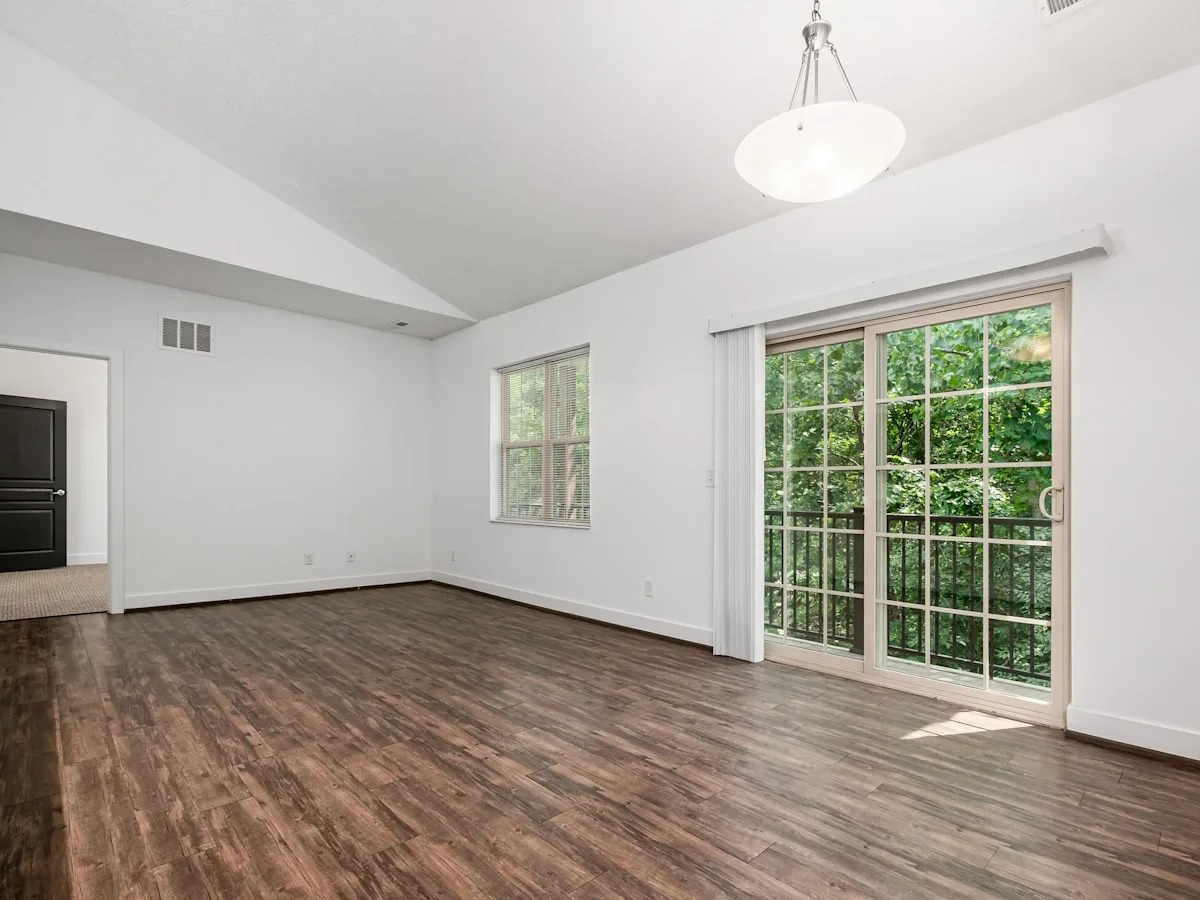 A room with a sliding glass door and wood flooring.