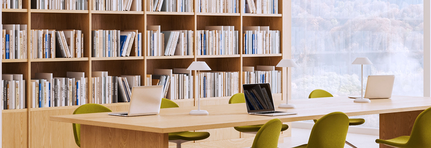 A modern, sun-filled library with light-washed wooden bookshelves and lime green chairs.