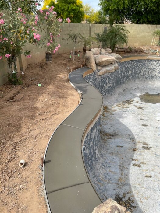 Custom concrete coping installation following the curves of an existing freeform swimming pool. The  
