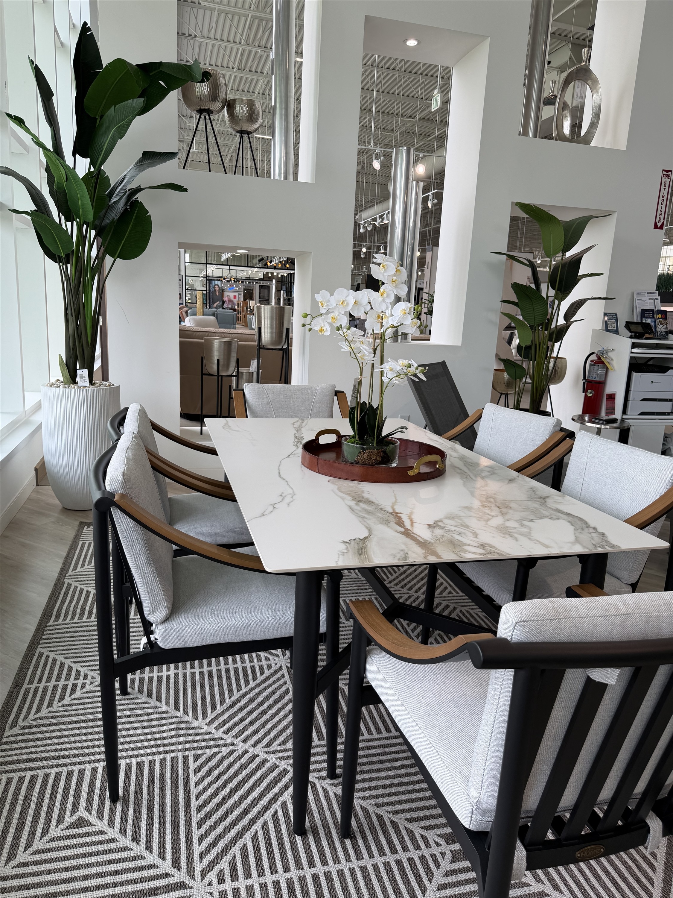 Elevate outdoor dining with this marble-look table and sleek black teak-accent chairs