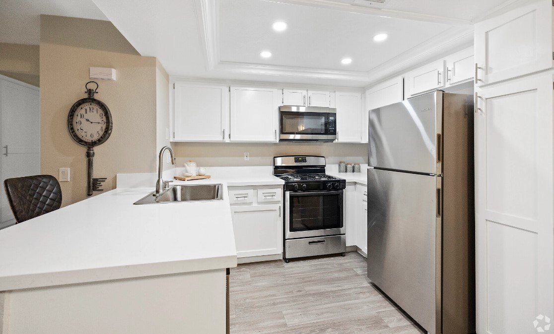 A modern kitchen with a white countertop and stainless steel appliances
