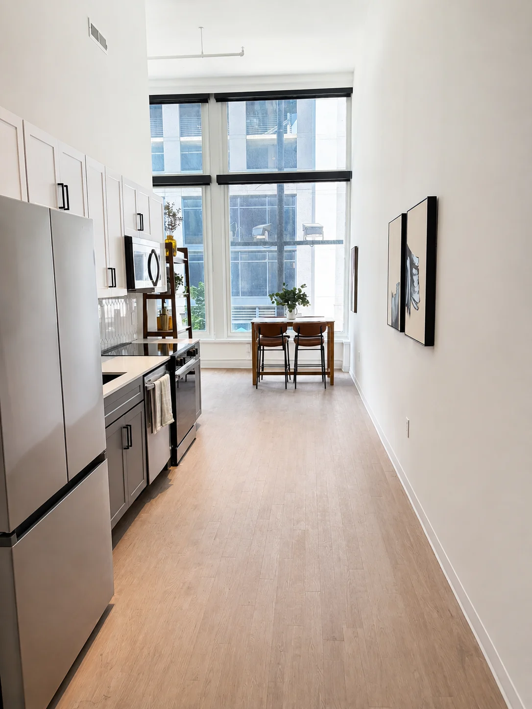 A kitchen with a refrigerator, a dining table and chairs, and a painting on the wall