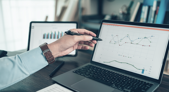 A wealth professional pointing at a graph on a laptop.