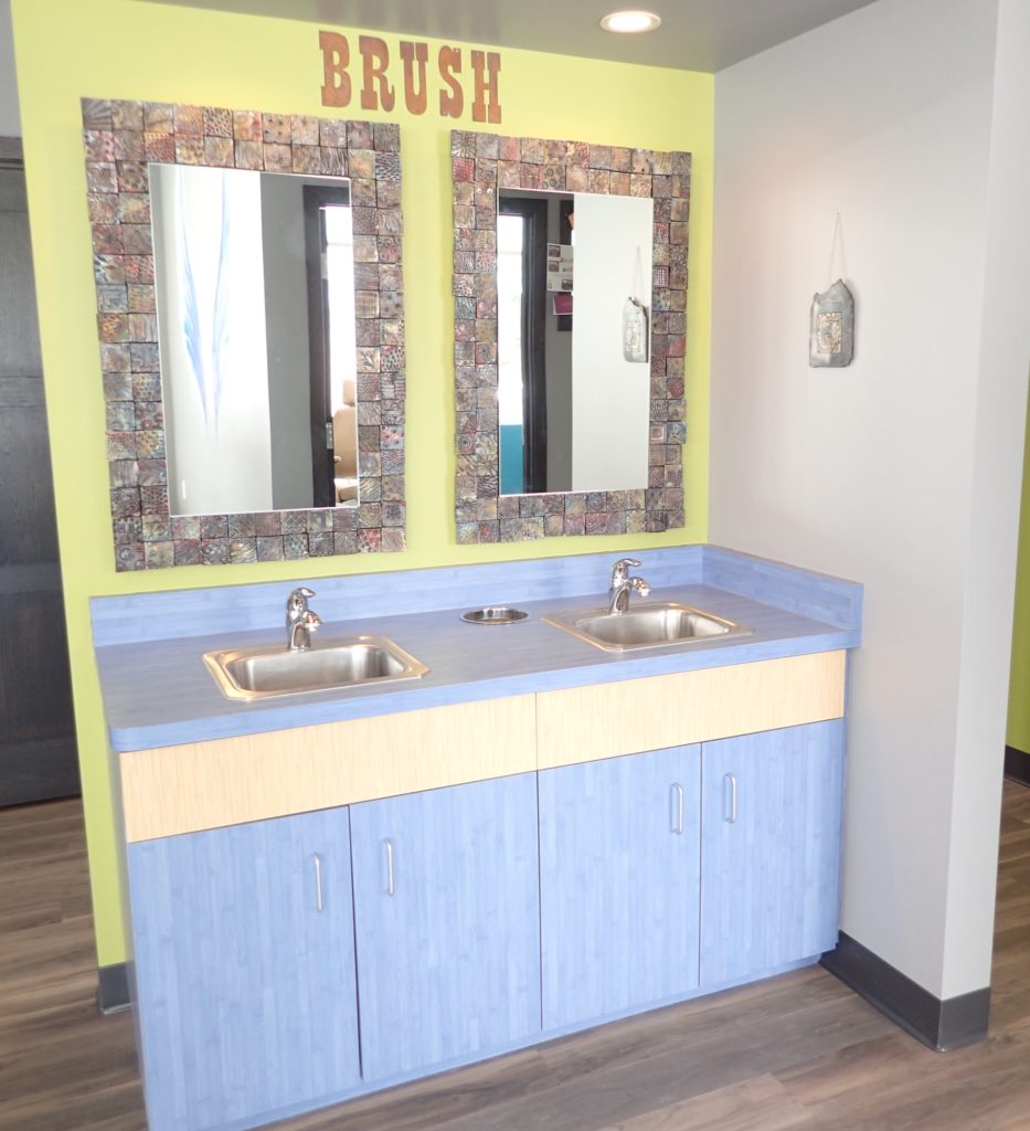 A bright and inviting bathroom at Imagine Orthodontics, featuring playful mirrors and a cheerful color scheme.