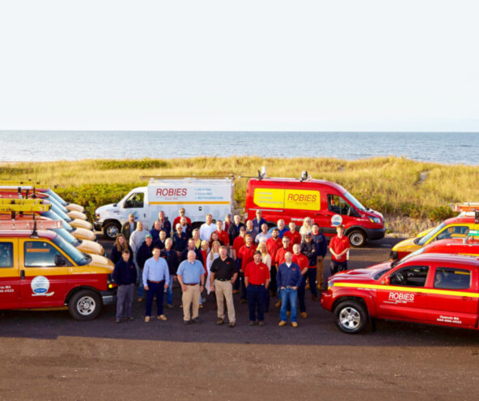 Robies employees in front of trucks at beach with grass and ocean in the background