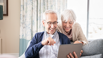 An elderly couple reviewing documents on their tablet.