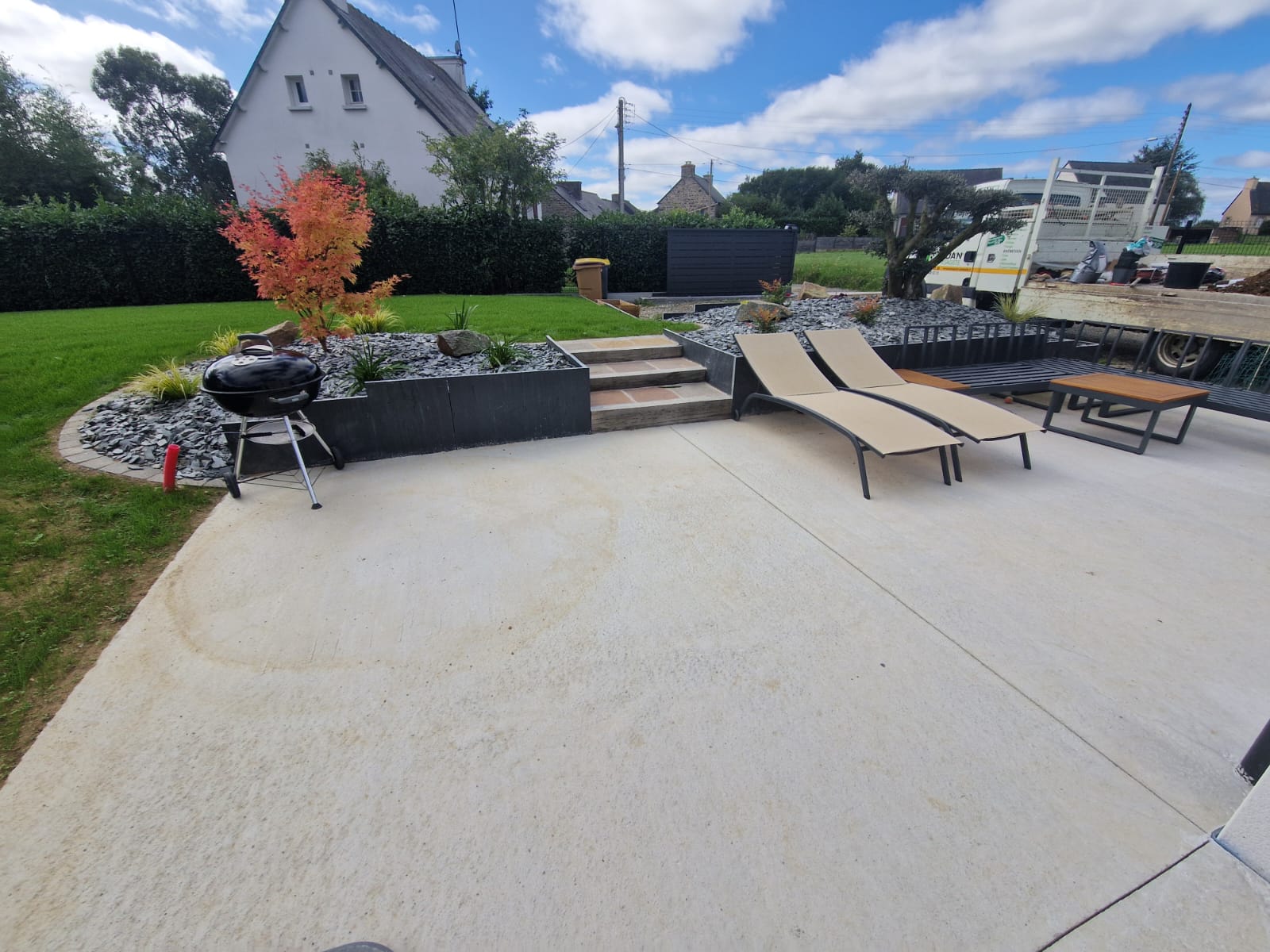 Terrasse béton, retenue de terre en ardoises, petit escalier, plantations.