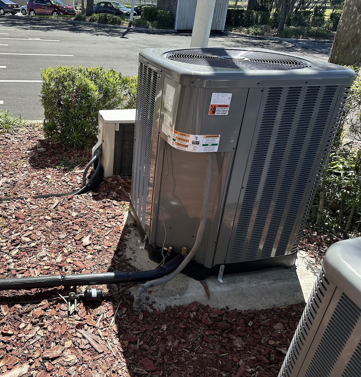 Residential AC condenser installed beside the home with professional refrigerant and electrical connections.