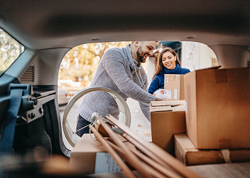 A couple unloading the trunk of their vehicle.