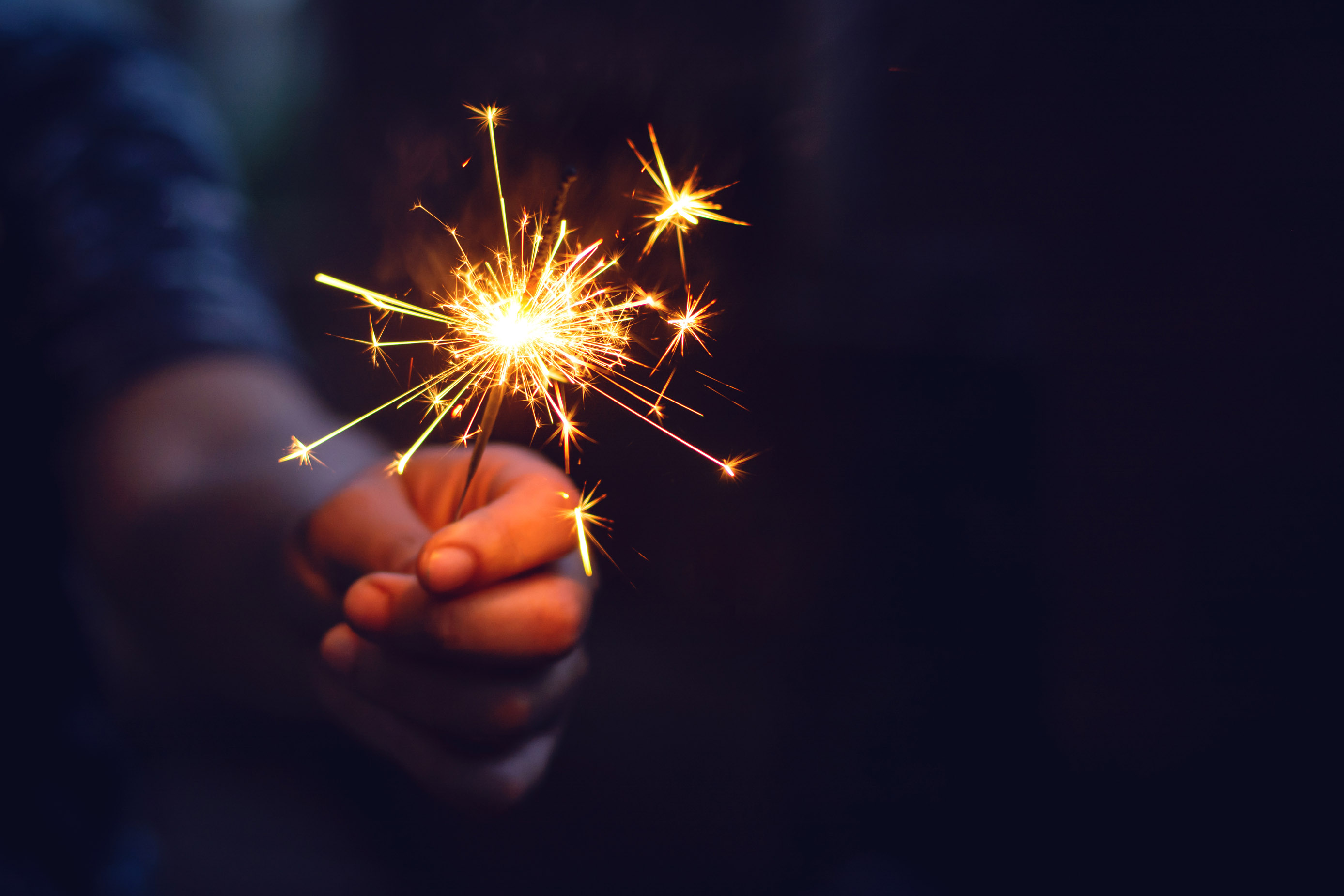 A child holds a sparkler, which is unsafe.