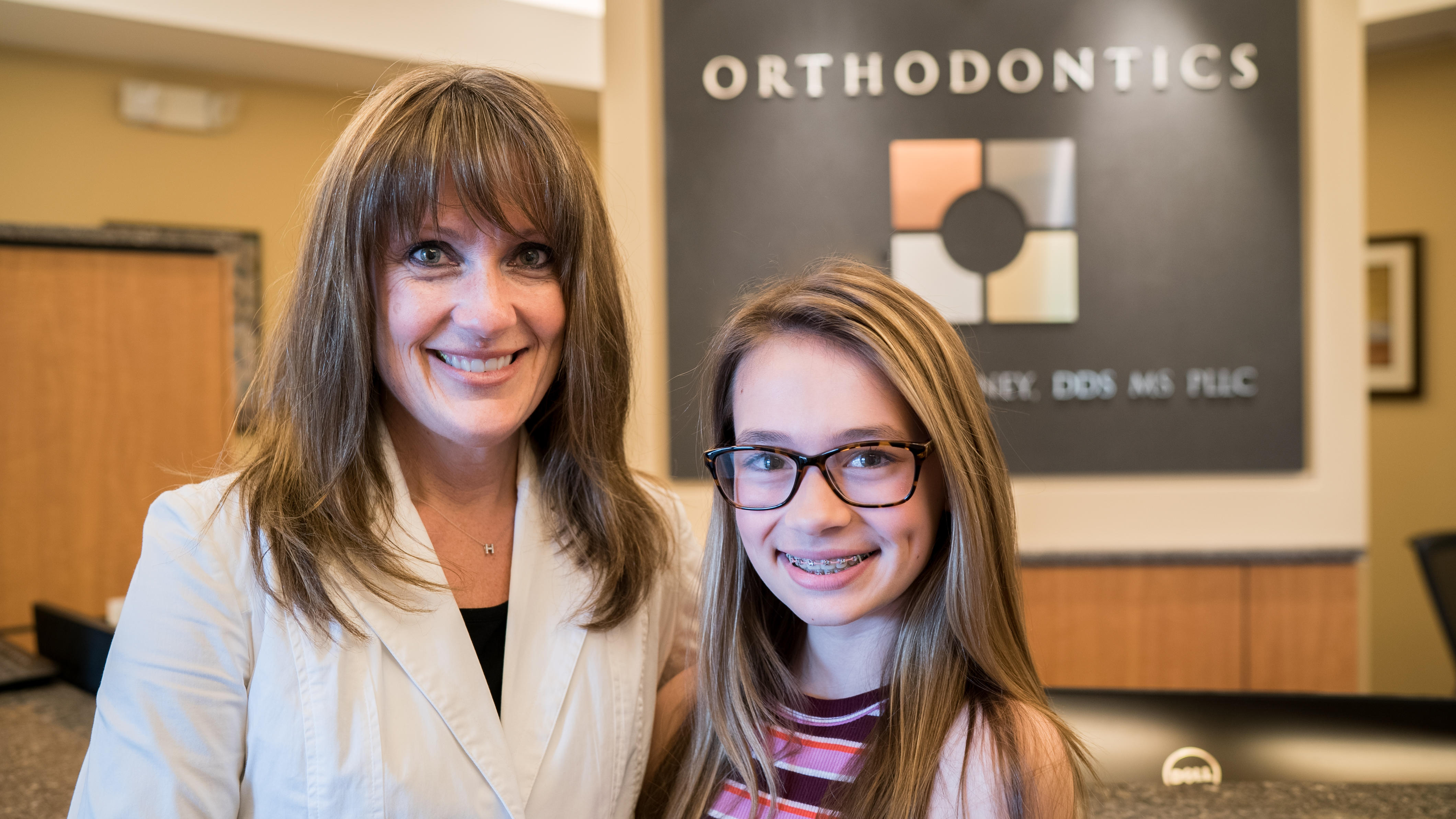 mother & teen daughter smiling at cooney orhthodontics office in ballston lake, ny
