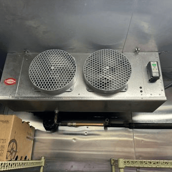 Commercial kitchen exhaust ventilation system with dual fan covers installed above food preparation area.