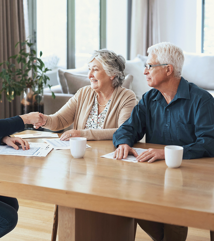 An elderly couple shaking hands with their financial advisor.