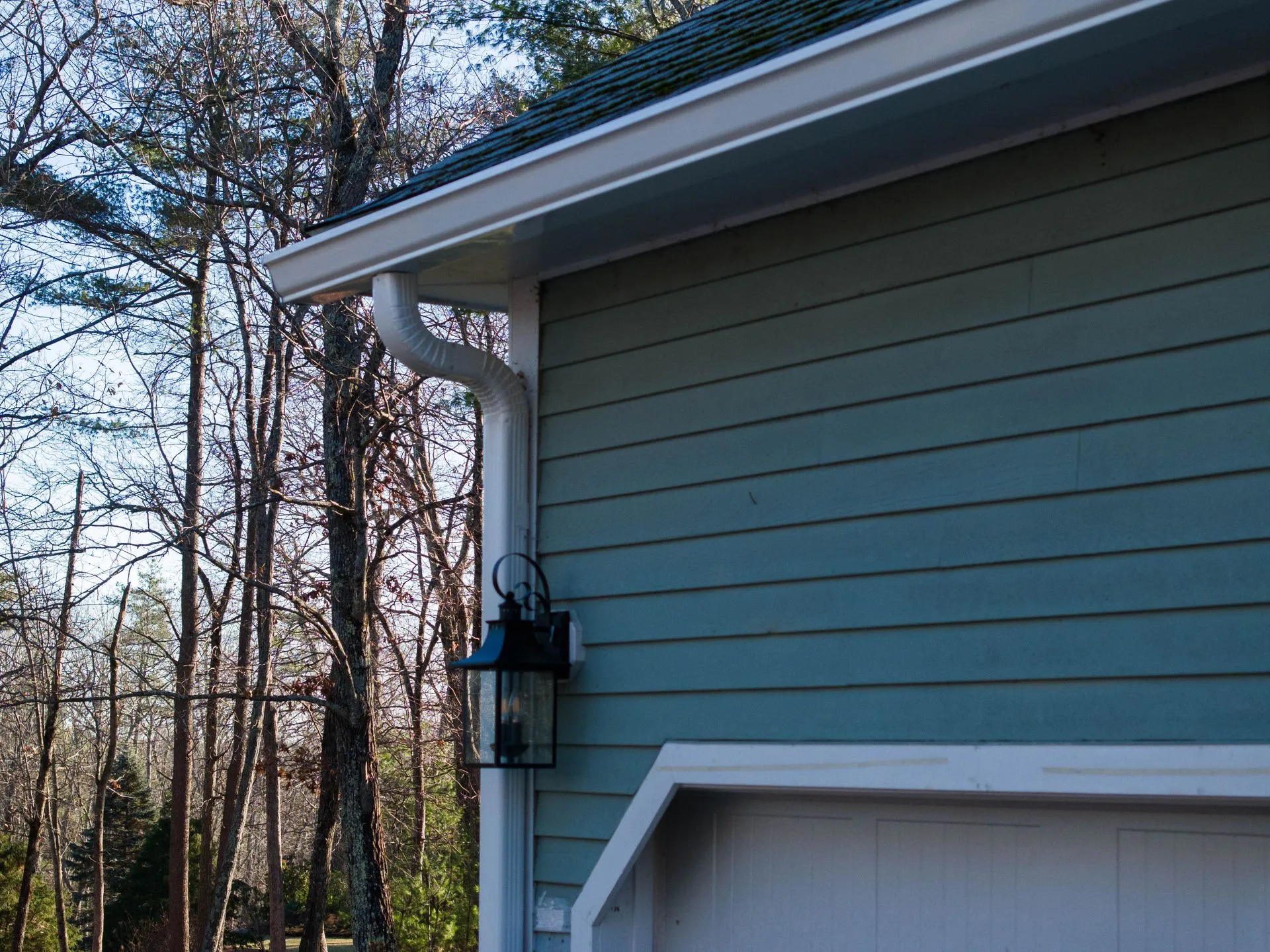 Residential home exterior featuring white seamless gutters along the roofline. Durable gutter system 