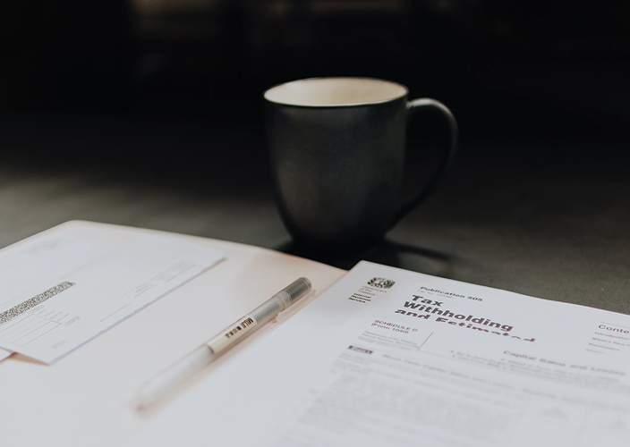 Close-up of documents with a coffee mug.