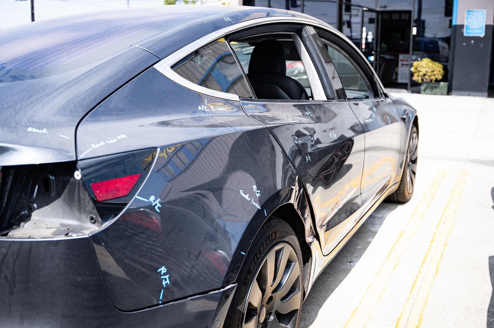 Detailed photo of Tesla Model 3 waiting at auto body shop parking lot for collision repair