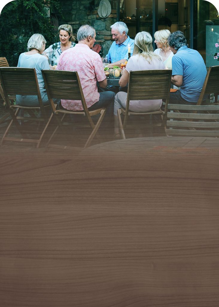 A multigenerational family gathered around a dining table in the backyard.