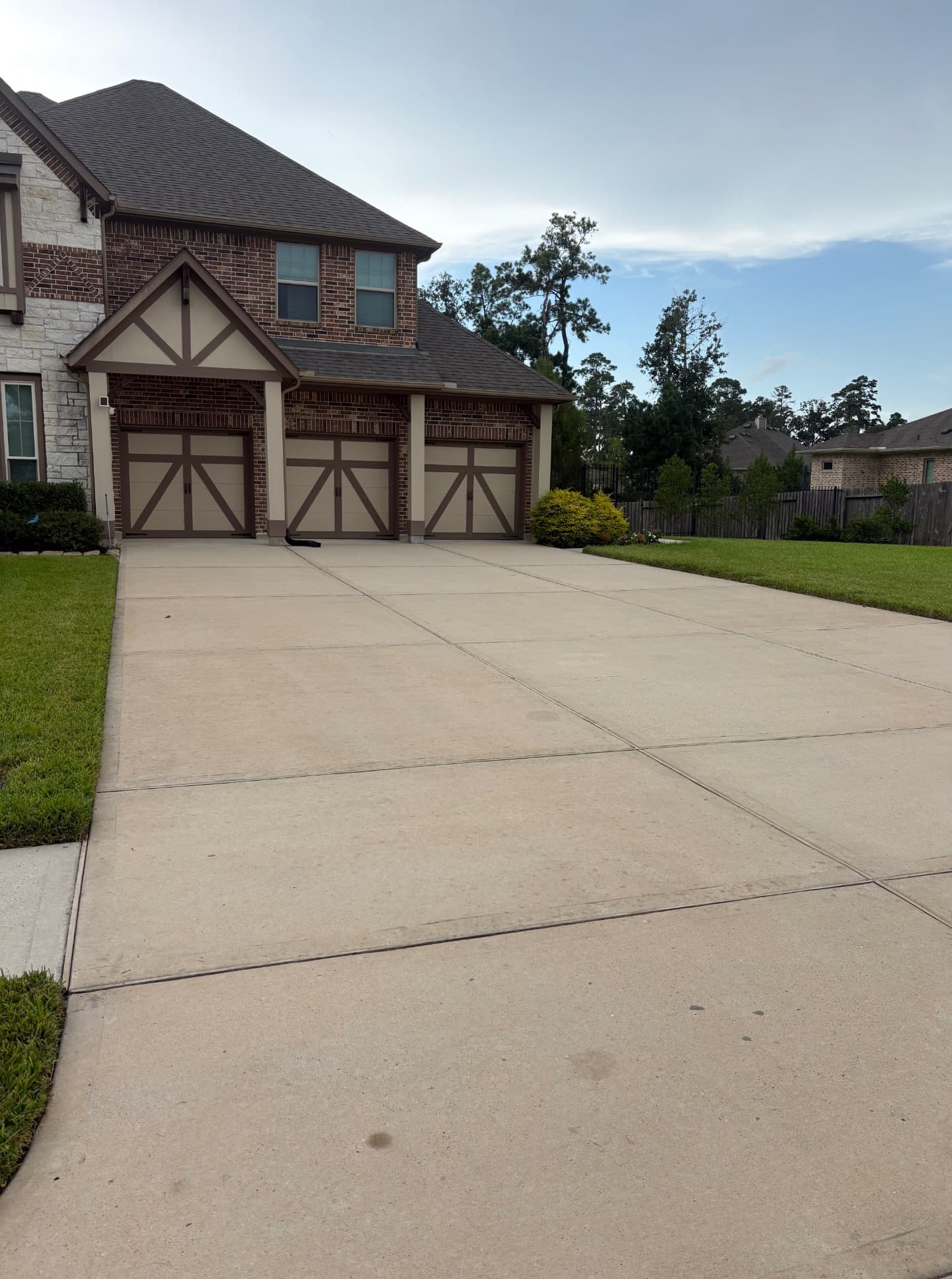 Freshly pressure-washed concrete driveway with dirt and buildup removed, showcasing professional driveway cleaning and pressure washing services in Conroe, TX by Integrative Soft Wash and Property