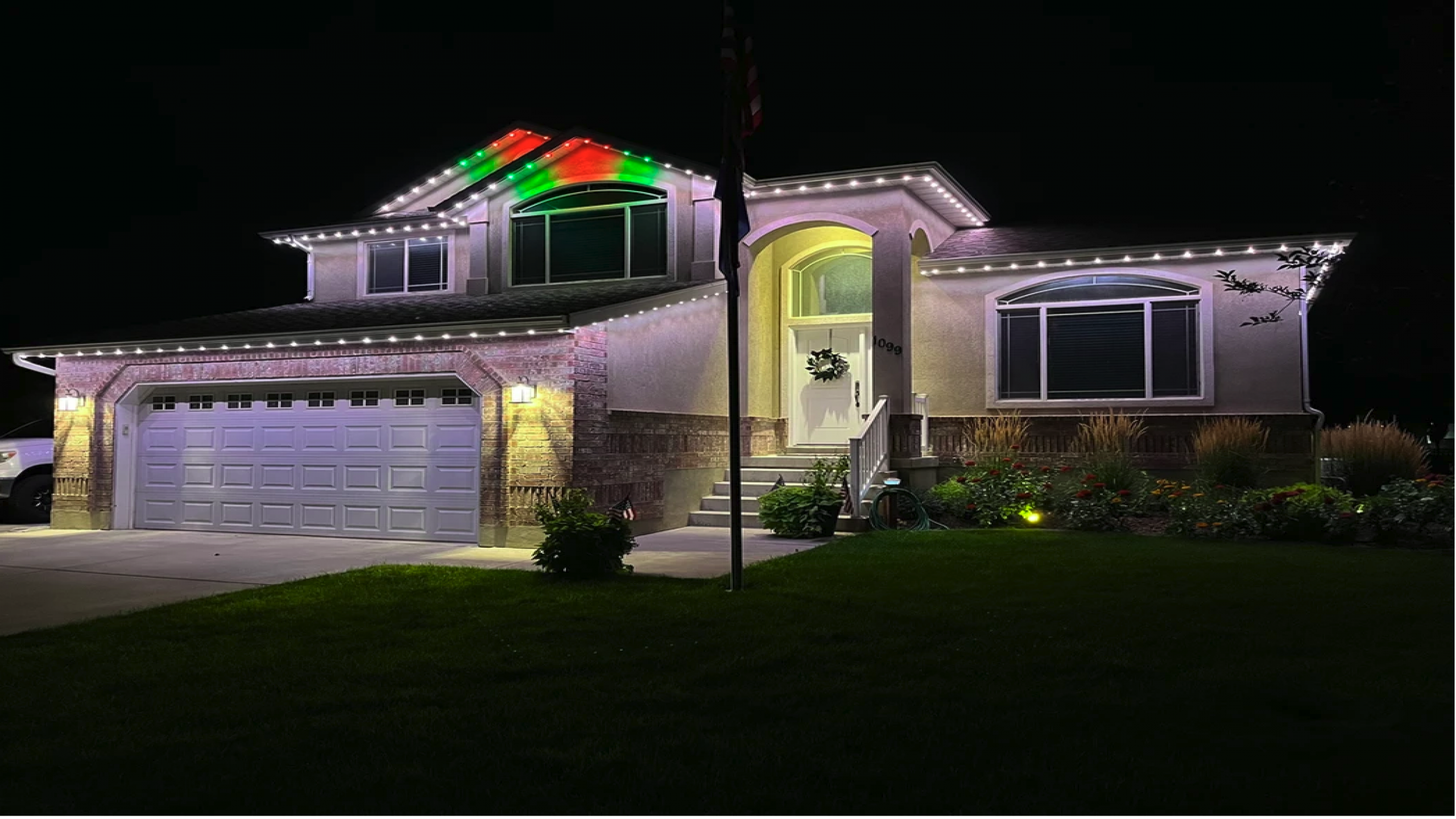 Custom multicolor permanent lighting outlining the roofline and exterior of a residential property at night.