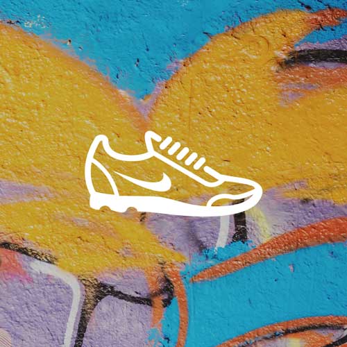 A white outline of a Nike sneaker with the iconic swoosh logo is superimposed over a vibrant, graffiti-covered wall. The wall features bold strokes of yellow, blue, and purple, creating a dynamic and urban backdrop.