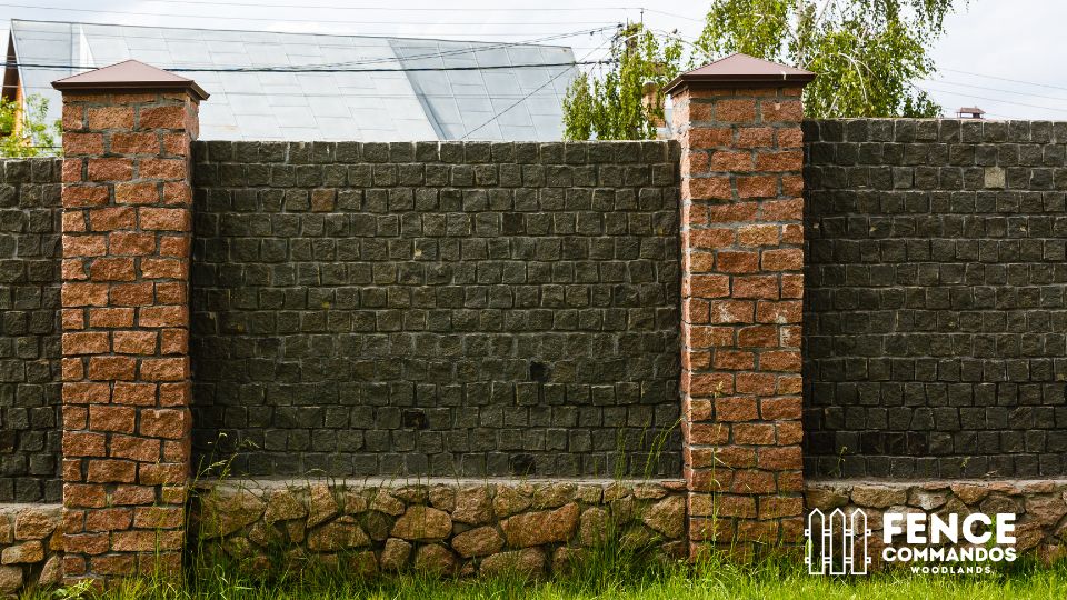 Durable wood and stone privacy fence featuring brick posts and a natural, rustic design.