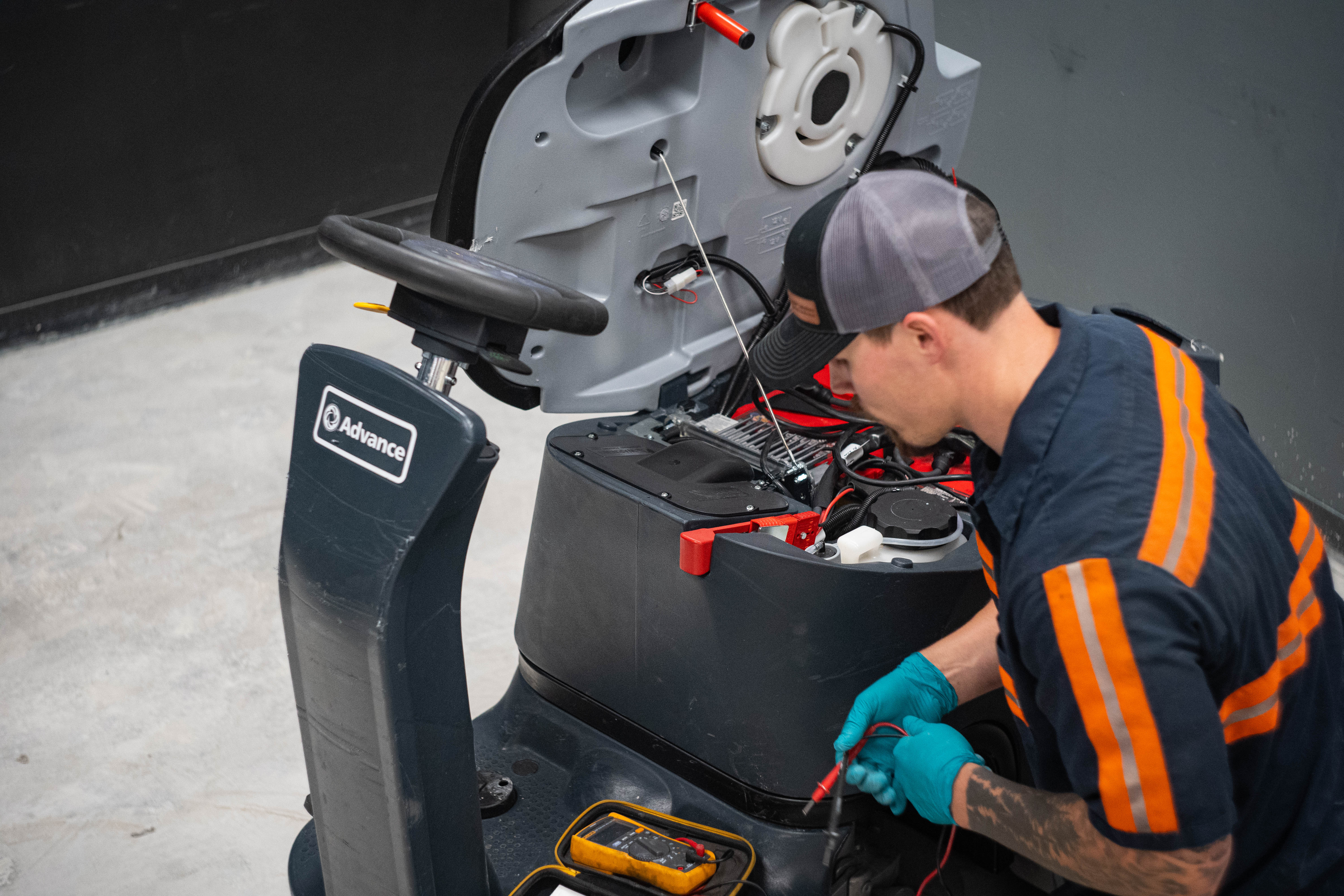 WaySolutions lead technician Kaden uses a precision digital multimeter to trace electrical currents within the internal control board of a heavy-duty Advance ride-on floor scrubber. Our advanced electrical diagnostics in Layton, Utah, accurately identify hidden wiring faults to keep your large-scale commercial cleaning equipment operating reliably.