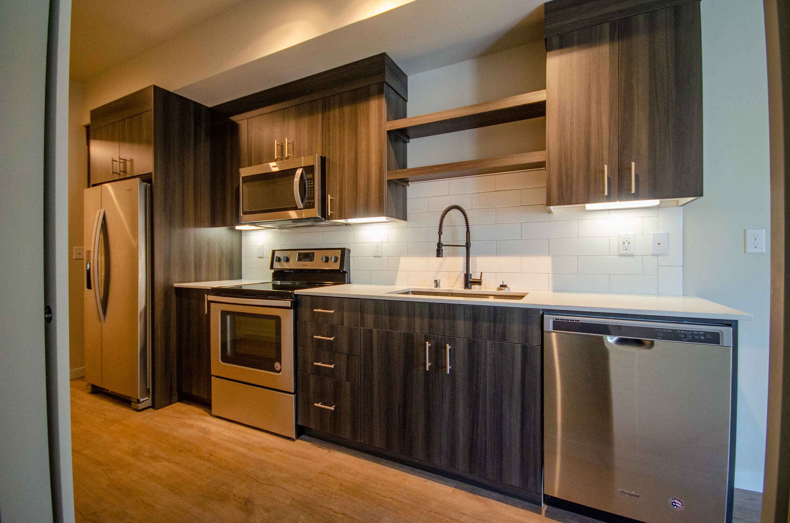A modern kitchen with dark wood cabinets and stainless steel appliances.