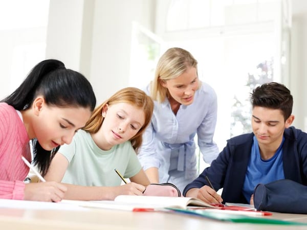 Nachhilfelehrerin unterstützt ihre Schüler beim Lernen am Tisch.