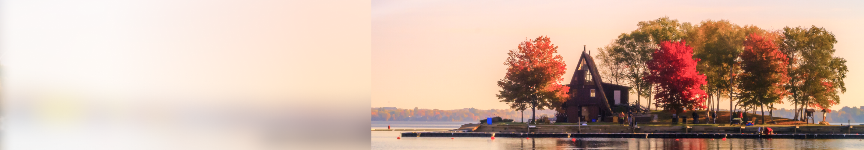 An A-frame lakeside cottage surrounded by colourful autumn trees.