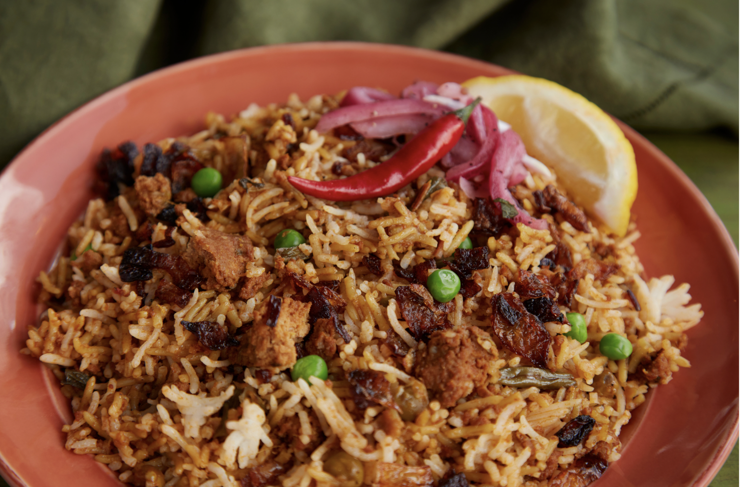 Lamb Biryani - - Boneless marinated lamb simmered in a mixture of spices and aromatics until tender.  Cooked with long grain basmati spiced rice. Garnished with fresh lemon, Thai chili pepper, fried and pickled onions.
- Gluten & Dairy Free