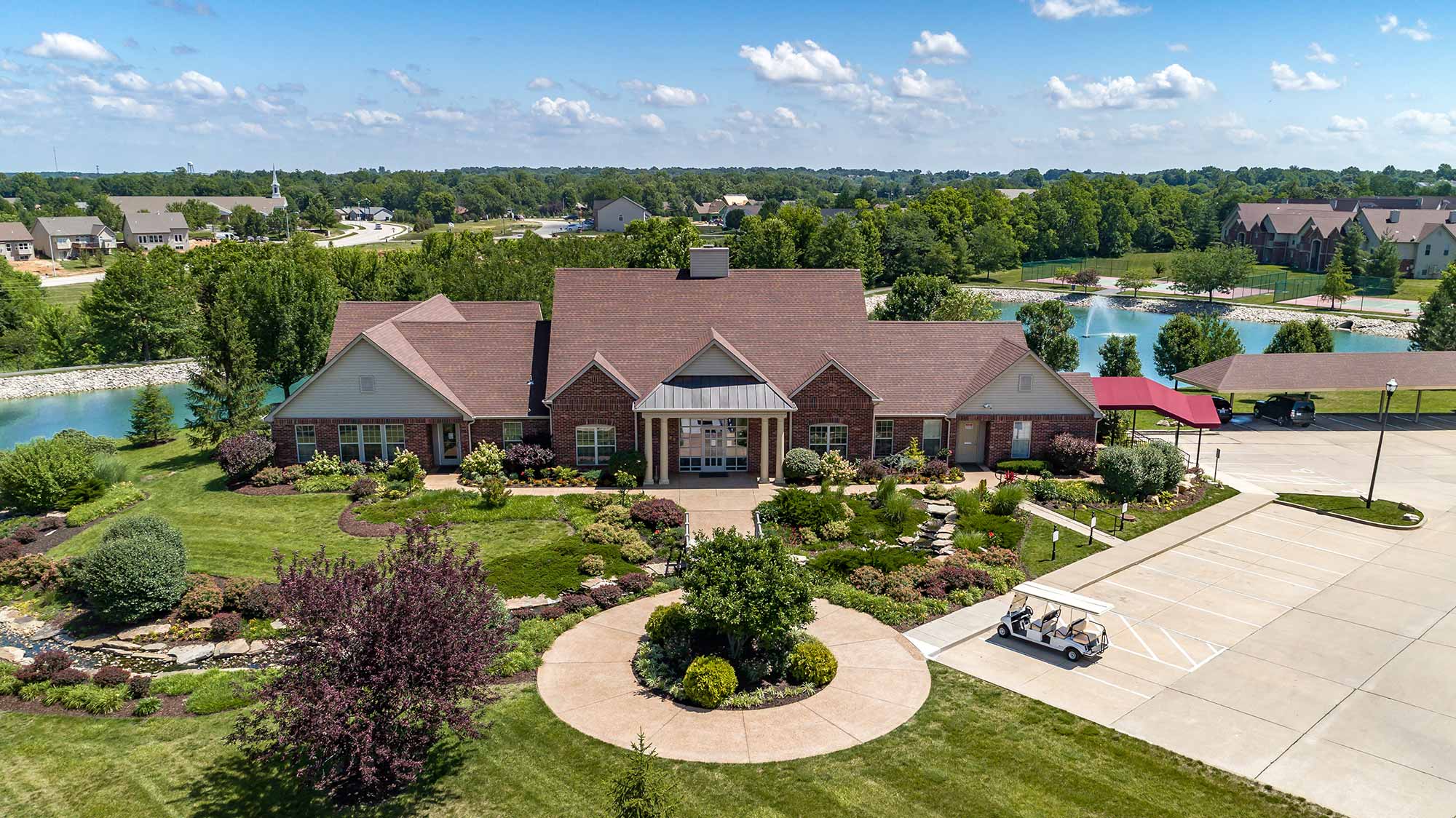 Exterior view of The Waterways of Lake Saint Louis' clubhouse, located close to a pond and well-maintained grounds.