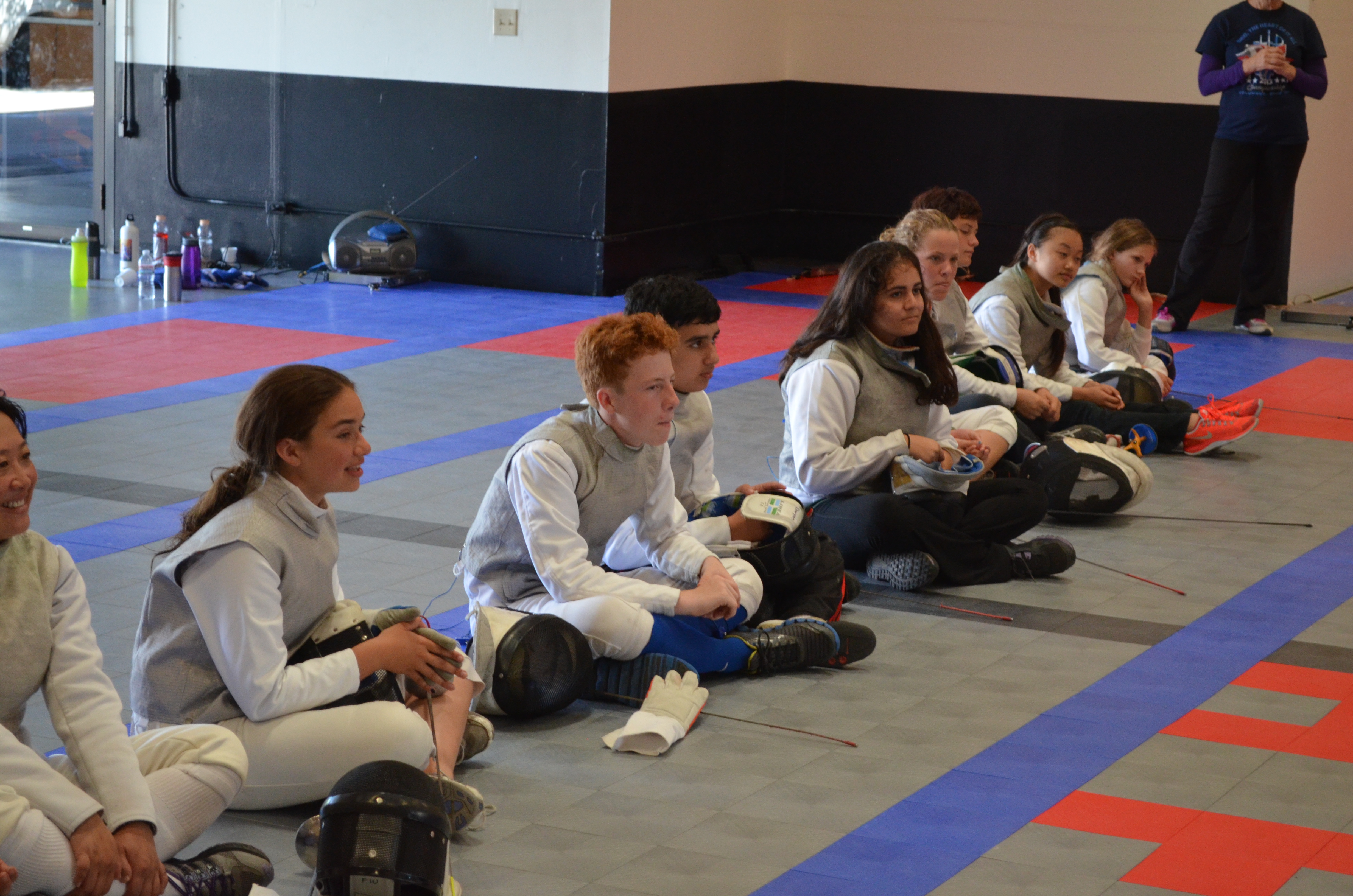 Foil fencers are watching a fencing bout at Academy of Fencing Masters
