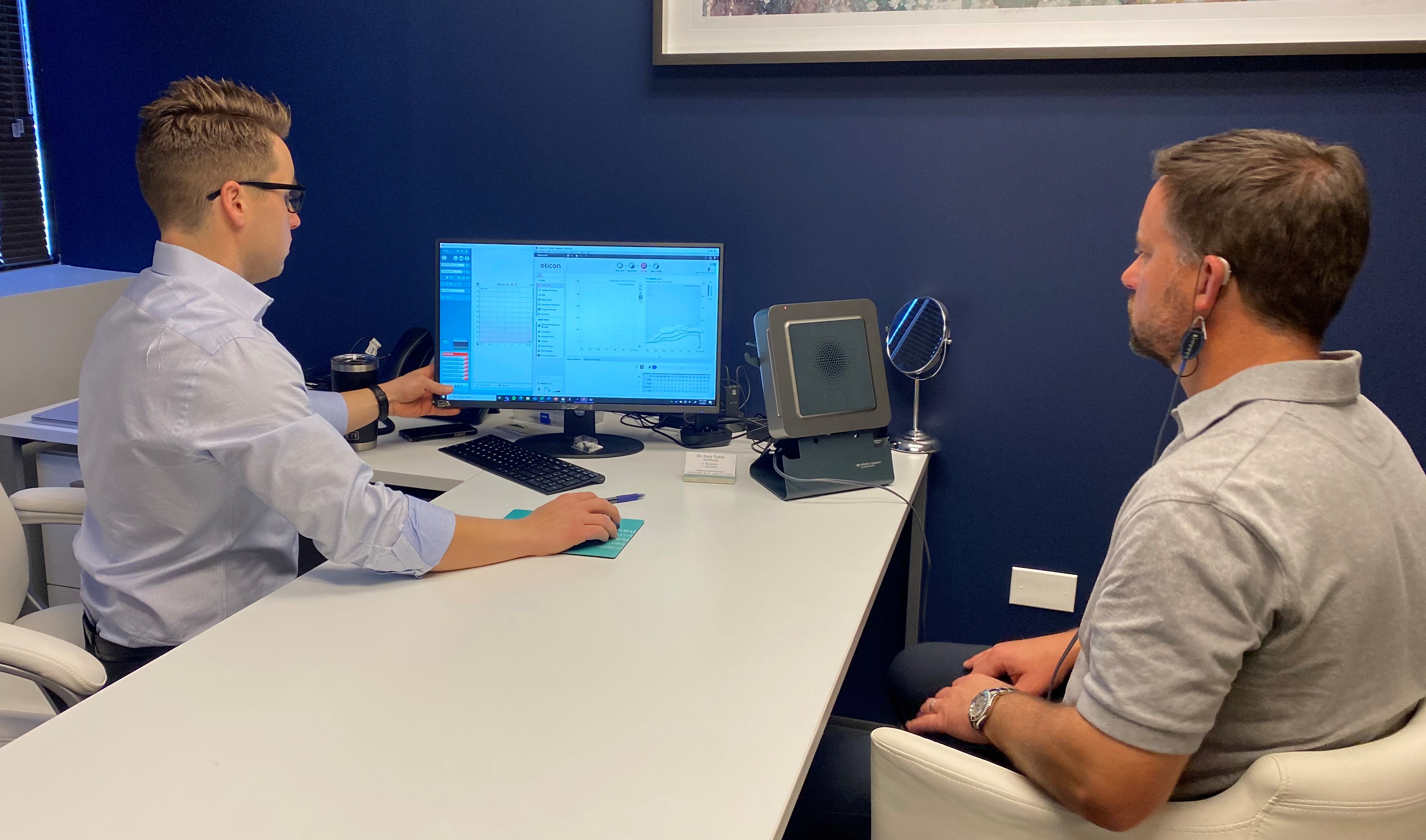 Cory Tickle (audiologist) and Matt Wilken (audiologist) illustrate what a hearing test looks like in the Colorado Ear Care Offices