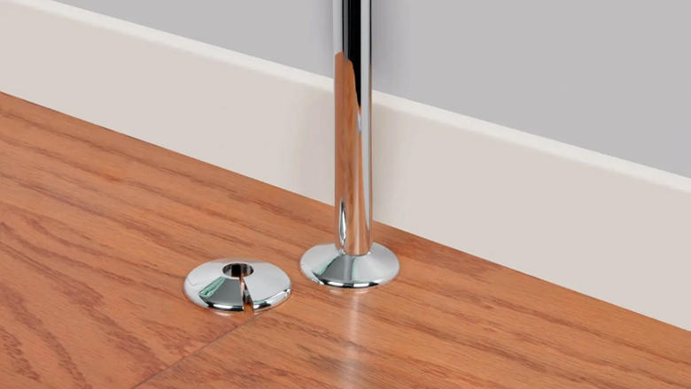 A silver rosette for a pole extending from laminate flooring