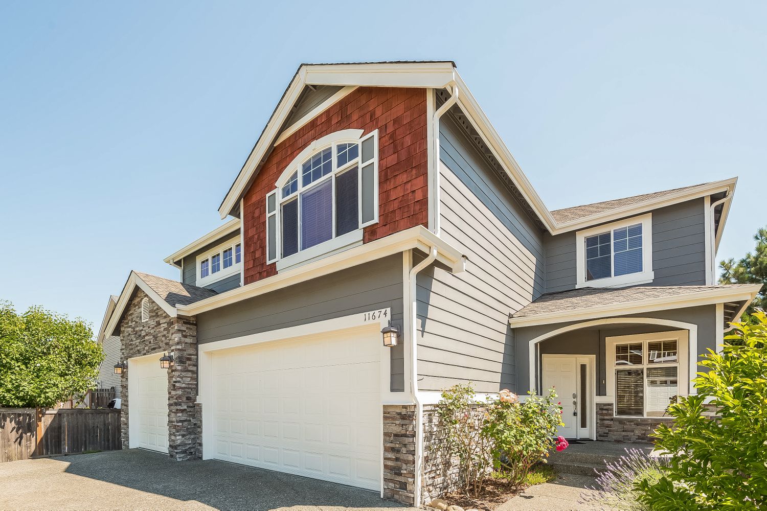 Front of home shot with a three-car garage and covered entry way at Invitation Homes Seattle.