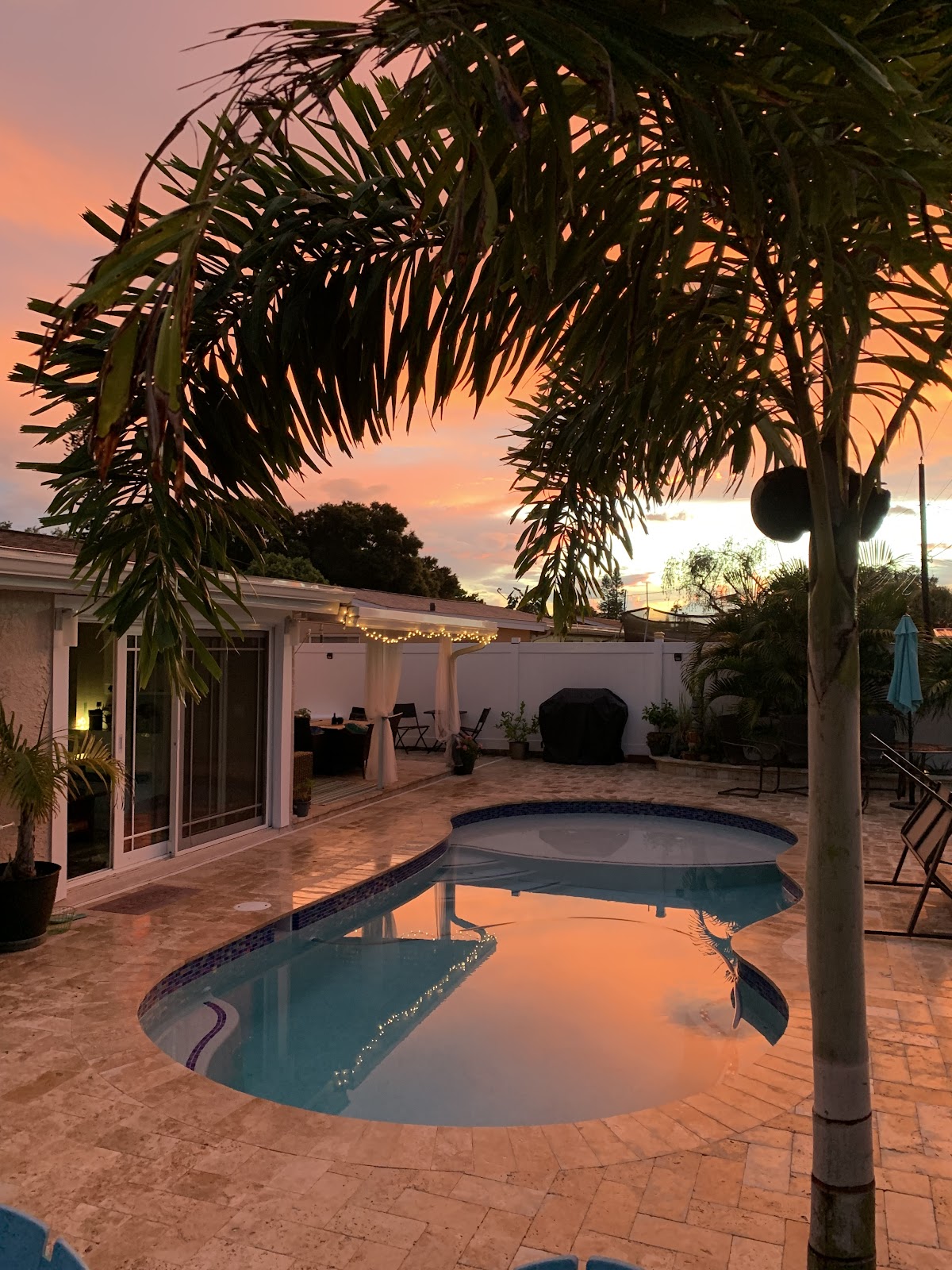 Backyard swimming pool at sunset with palm trees, warm sky reflections, and a relaxing tropical patio setting.Backyard swimming pool at sunset with palm trees, warm sky reflections, and a relaxing tropical patio setting.
