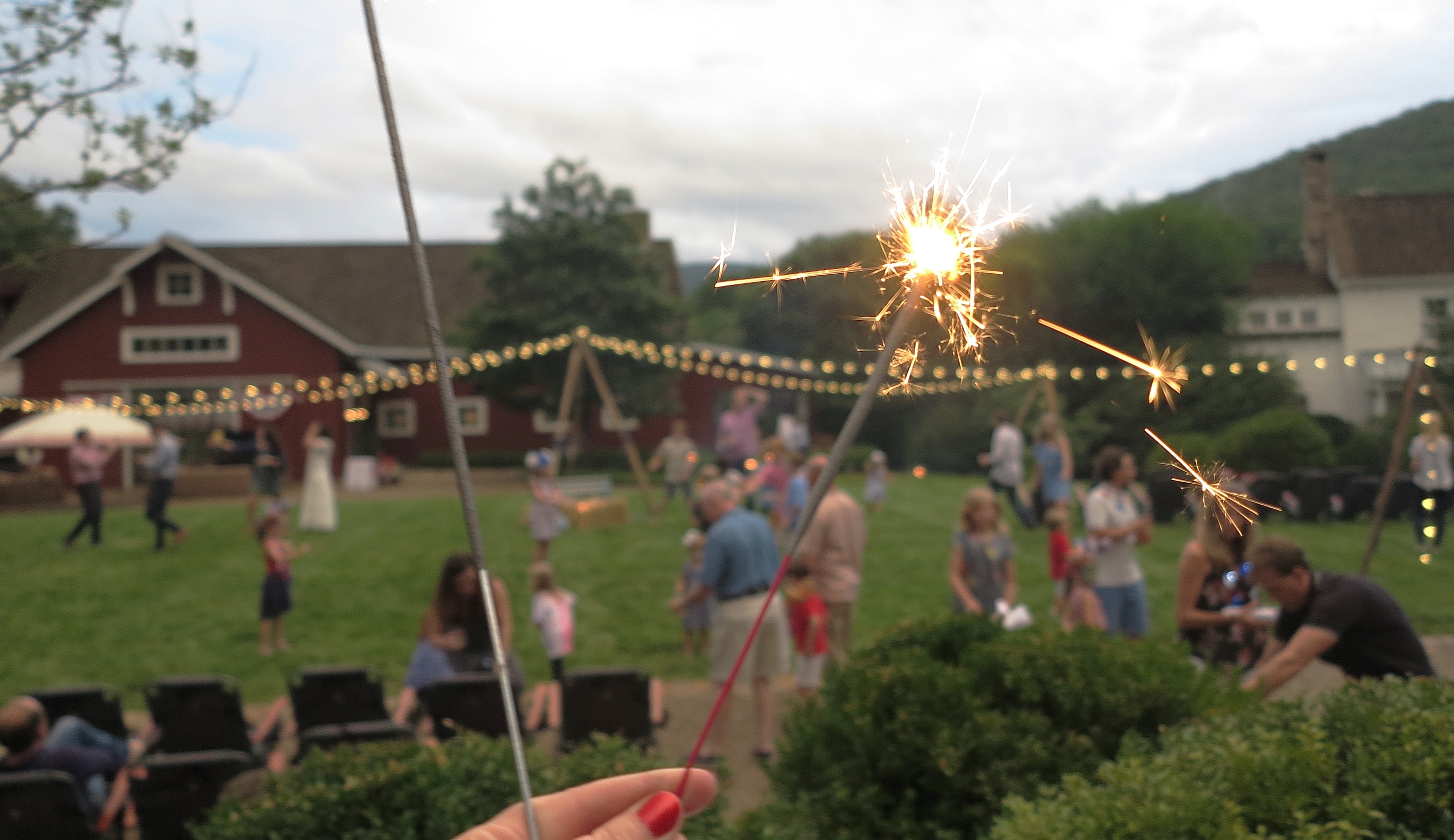 Guests celebrating on the ranch lawn decorated with glowing string lights and sparklers, capturing the festive evening atmosphere and community gatherings during the fall season.
