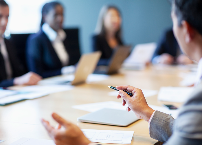 A business meeting with professionals around a boardroom table.