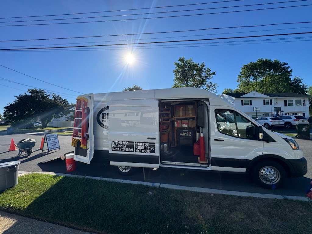 Brick Industries service vehicle parked outside a residential property with asbestos work signage and safety cones set up near the job area.