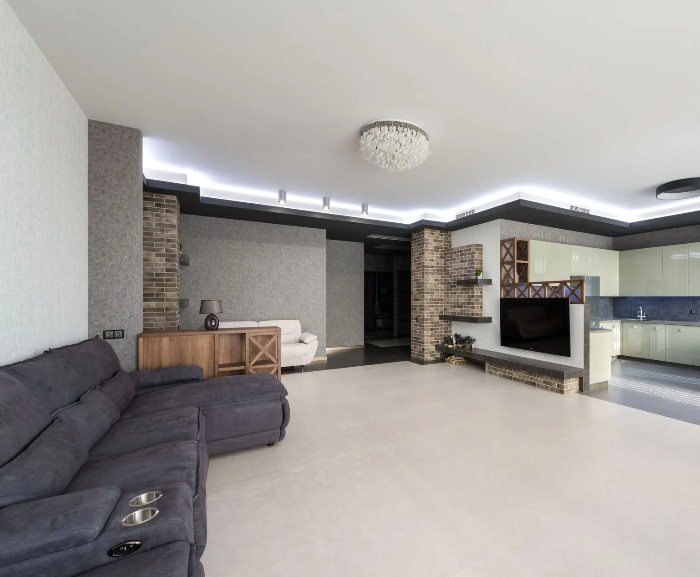 Open-concept finished basement transformation with modern tray ceiling LED lighting, exposed brick p 