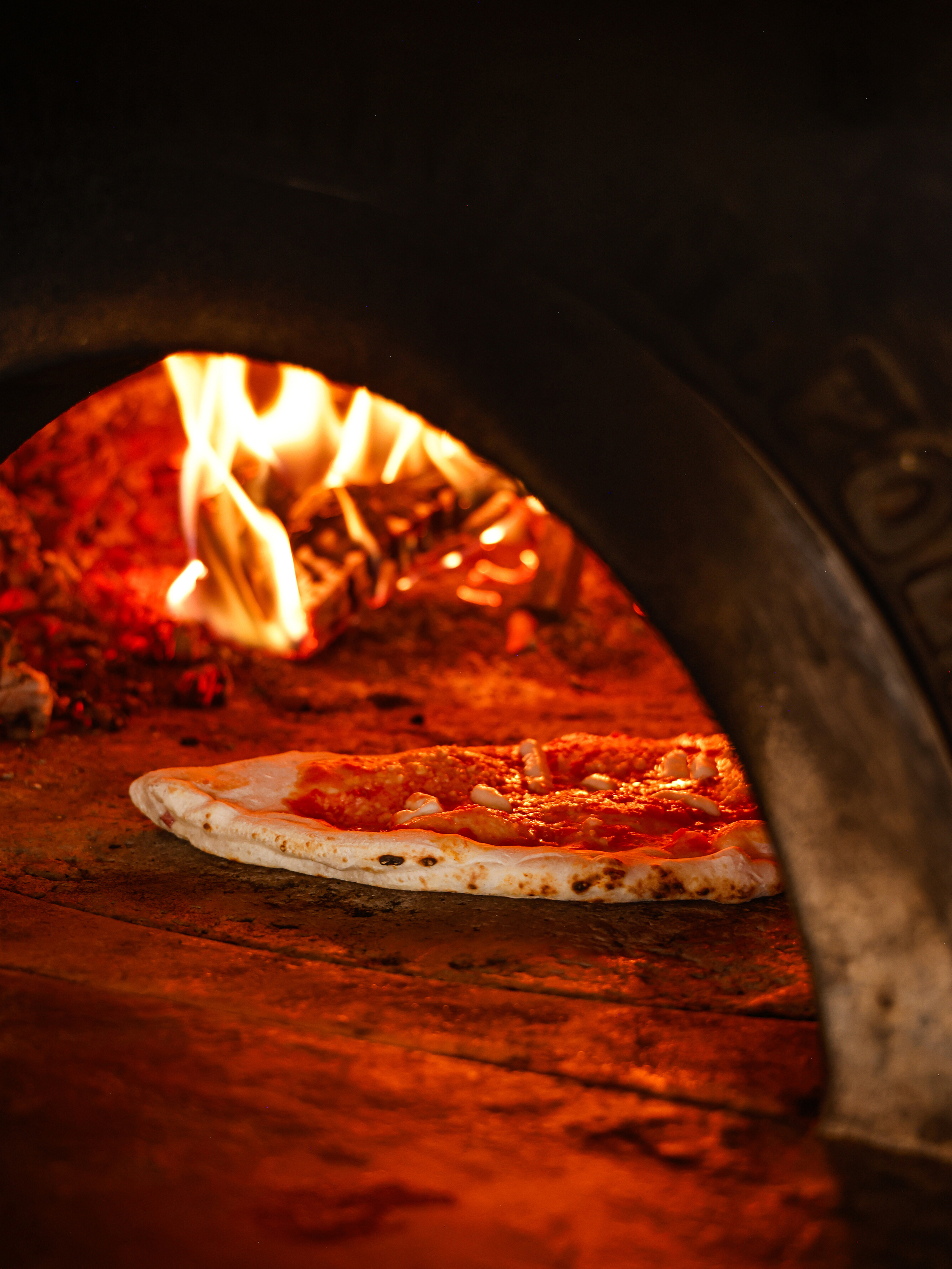 Authentic Neapolitan pizza baking in a traditional wood-fired oven. 