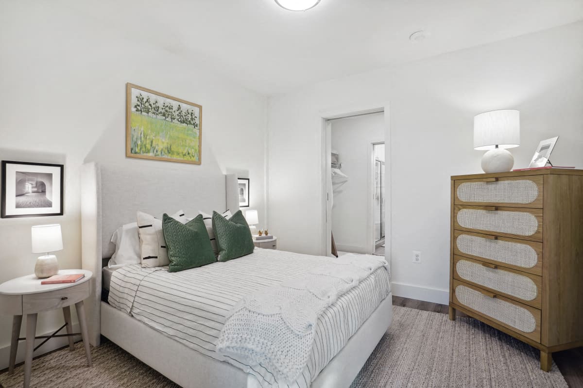 a bedroom with a bed and a dresser and a bathroom