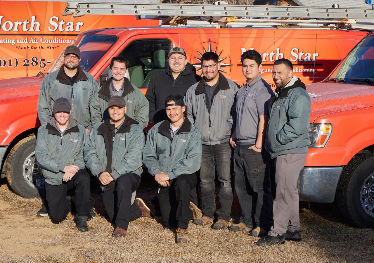 The North Star Heating & Air Conditioning company HVAC team. Standing in front of our orange work vans.
