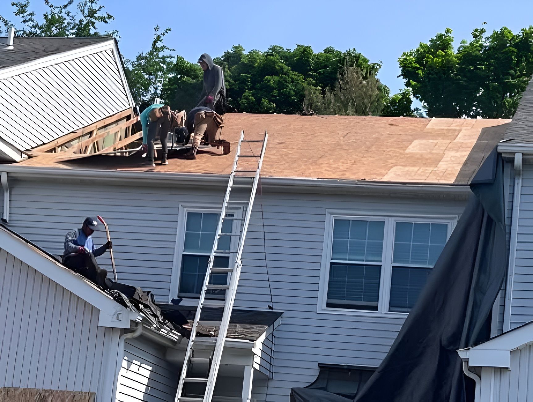 Roofing crew removes old materials and prepares decking for a complete roof replacement. Professiona 