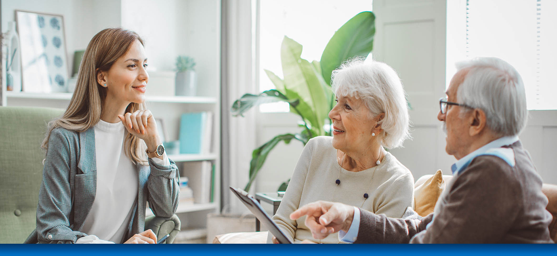 An advisor meeting with an elderly couple to review documents.