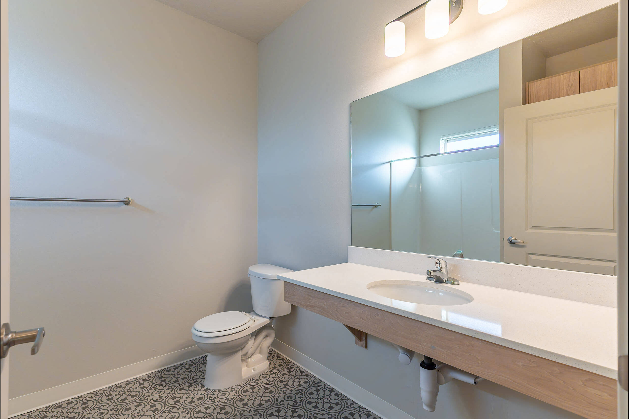 A bathroom with a toilet, sink, and mirror.
