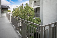 Third-floor walkway with view of tree from courtyard.